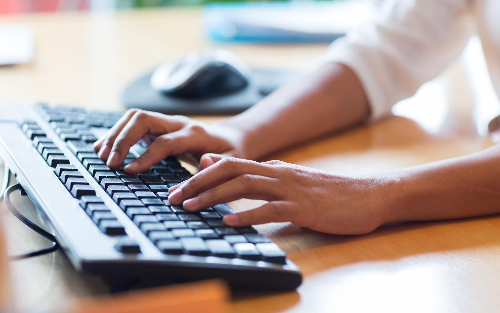 close-up of hands on a computer keyboard